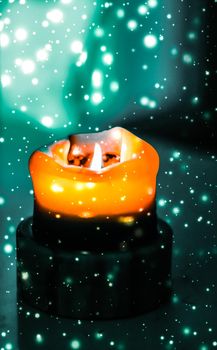 Happy holidays, greeting card and winter season concept - Orange holiday candle on green sparkling snowing background, luxury branding design for Halloween, New Years Eve and Christmas