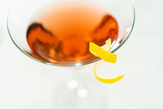 Cosmopolitan cocktail in a martini glass and decorated with a lemon swirl.