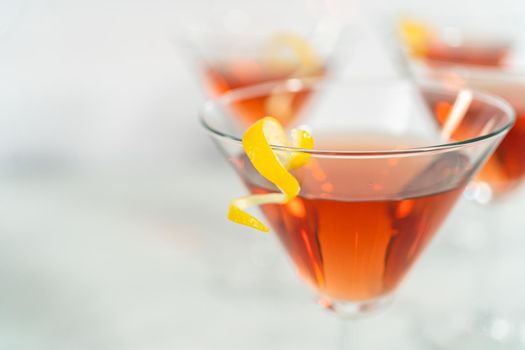 Cosmopolitan cocktail in a martini glass and decorated with a lemon swirl.