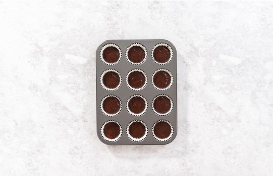 Flat lay. Scooping chocolate cupcake dough into the cupcake liners.