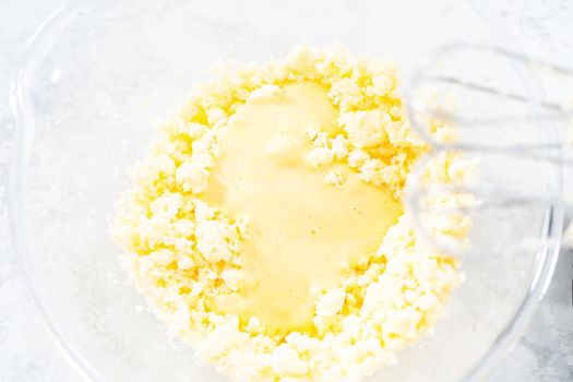 Close up view. Mixing ingredients in a glass mixing bowl to bake funfettti bundt cake.