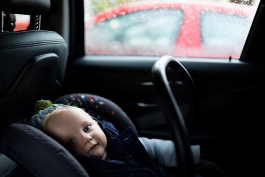 baby sitting in a car in a carrier, photo with depth of field. Child safety concept.