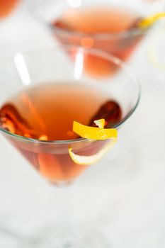 Cosmopolitan cocktail in a martini glass and decorated with a lemon swirl.