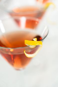 Cosmopolitan cocktail in a martini glass and decorated with a lemon swirl.