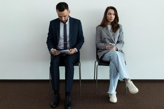 two young professionals in business suits waiting in line for an interview.