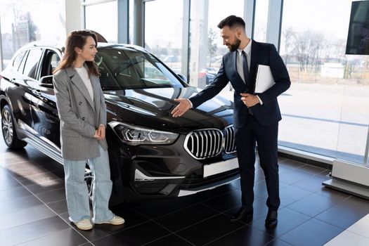 a representative of a car dealership demonstrates a car to a buyer.