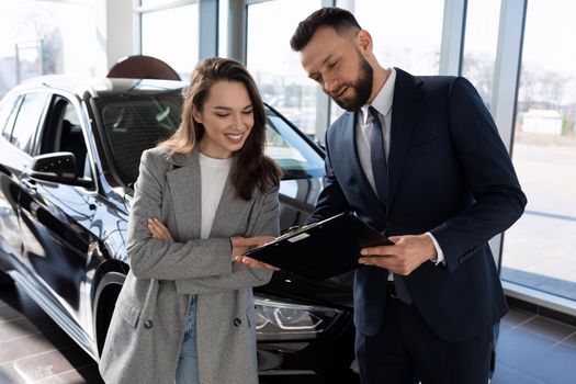 car dealership consultant talks about the loan program to the buyer of a new car.