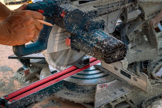 Miter saw. Cutting of PVC profile for siding. Sawdust. Selective focus