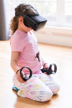 Little girl playing virtual reality game in the living room,