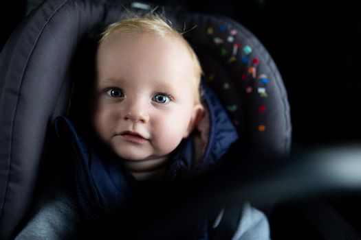portrait of a cute baby in a car seat in a car.