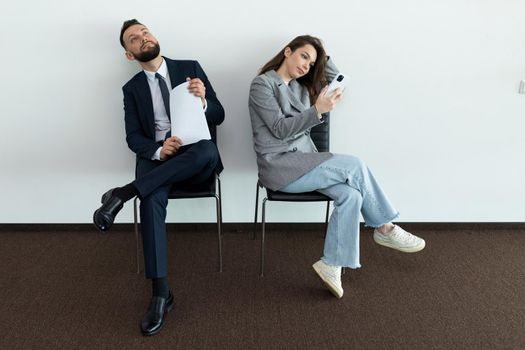 office employees sit on chairs man and woman waiting for an interview.