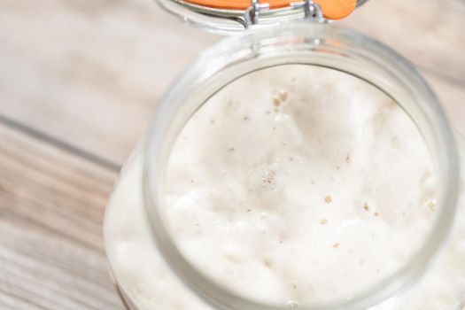 Feeding sourdough starter in a glass mason jar for baking artisan bread.