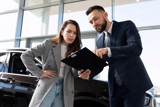 young woman buyer in a car dealership understands the nuances of the contract when buying a new car.