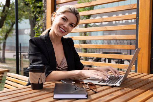 portrait of a charming woman working on a laptop in a cafe with a glass of coffee.