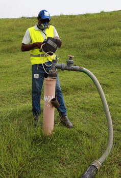 salvador, bahia / brazil - july 15, 2015:  Landfill employee measures methane gas produced on site. The product is used as fuel from a thermoelectric power plant.