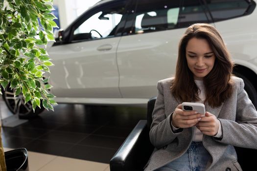 young woman in a car dealership waiting for the manager at the reception.
