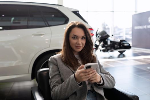 young woman in a car dealership waiting for a sales manager of new cars.