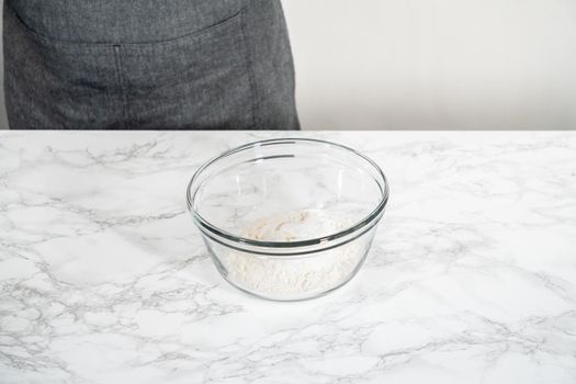 Mixing ingredients in a large glass mixing bowl to bake banana oatmeal muffins.
