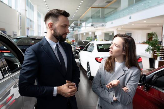 a young woman in a car dealership is interested in the terms of a loan to buy a new car.