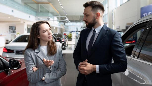 young woman in a car rental chooses a car for a long lease.