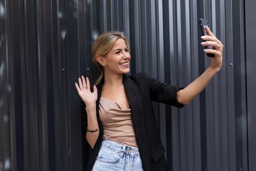 woman entrepreneur talking on video call using smartphone in office on gray wall background.
