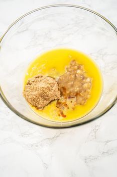 Mixing ingredients in a large glass mixing bowl to bake banana oatmeal muffins.