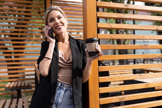 successful middle-aged woman during a lunch break in a cafe talking on the phone drinking coffee.