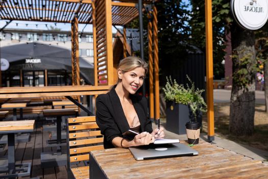 young business woman works in a cafe and drinks coffee.