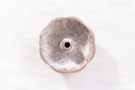 Flat lay. Greased metal bundt cake pan to bake chocolate bundt cake with chocolate frosting.
