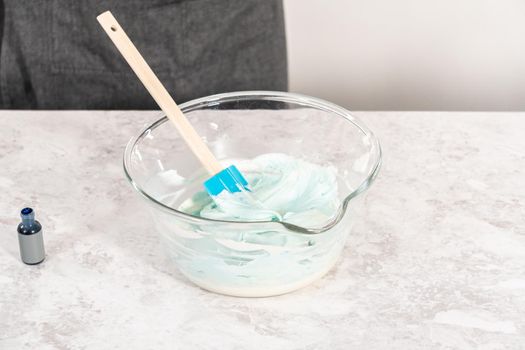 Mixing in blue food coloring into the buttercream frosting.
