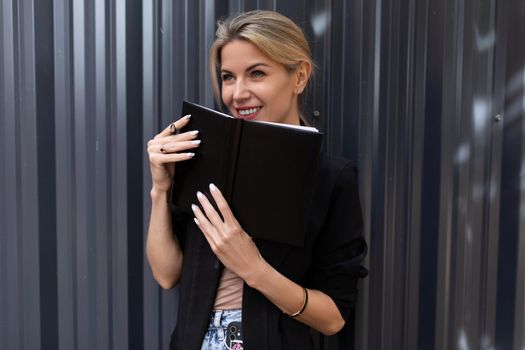 middle-aged woman office worker holding a notebook with a smile looking at the camera.