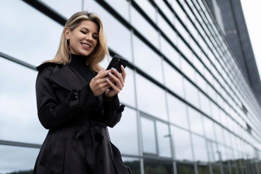 Middle-aged business woman with a mobile phone against the backdrop of an office building.