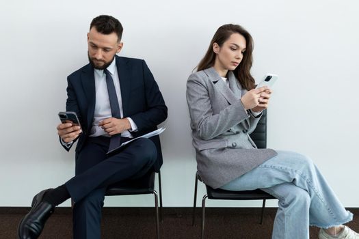 job seekers looking at their phones while waiting for an interview.