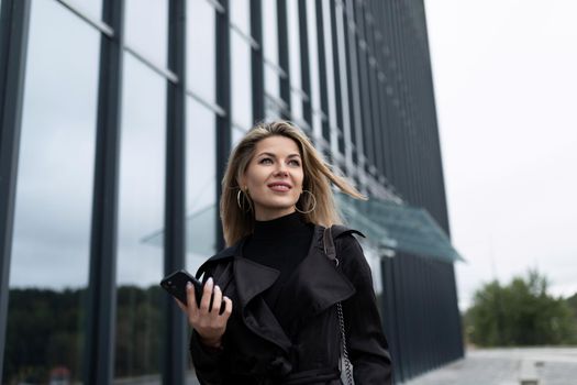 middle-aged businesswoman next to an office building looks dreamily into the distance.