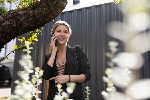 confident woman speaks on a mobile phone against the background of a gray wall in the city.