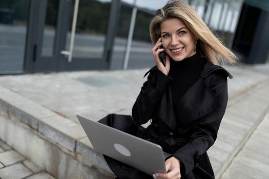 modern woman head successful businessman working online with a laptop on the background of an office building.