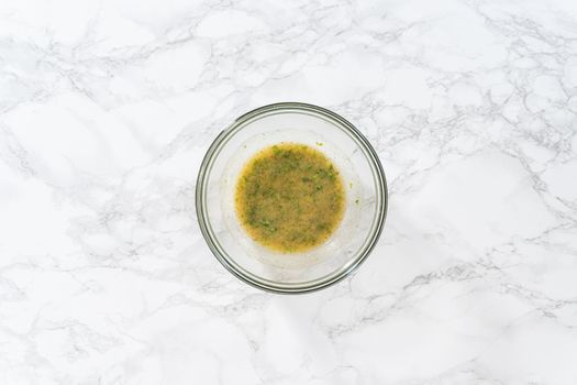 Flat lay. Mixing ingredients in a glass mixing bowl to prepare butter mixture for garlic lobster tails.