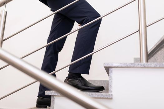 close-up of the legs of a businessman climbing the stairs, the concept of a successful business and career growth.