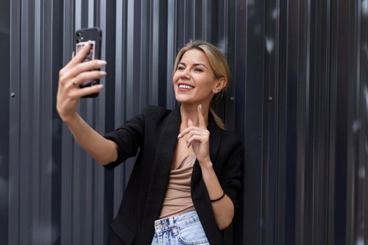 young woman talking on video call in office against gray wall.