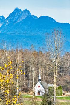 Small white church on autumn season in sunlight.