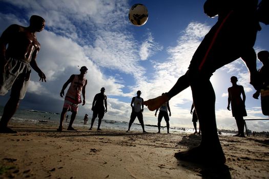 salvador, bahia, brazil - december 22, 2015: Young people are seen playing soccer on Itapua Beach in Salvador