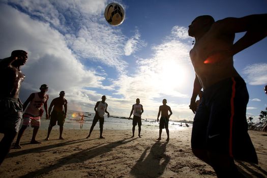 salvador, bahia, brazil - december 22, 2015: Young people are seen playing soccer on Itapua Beach in Salvador