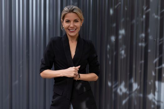 Portrait of a smiling middle-aged woman against a gray embossed wall.