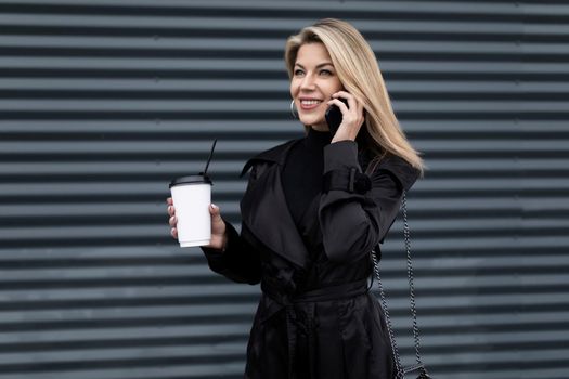 middle-aged woman executive talking on a mobile phone against a gray texture wall.