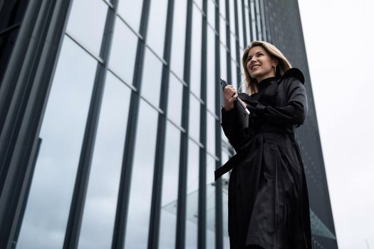 portrait of a confident woman businessman next to a glass office building with a smile looking into the distance.