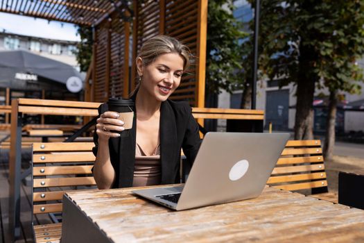 strong businessman drinking coffee i working on laptop outdoors.
