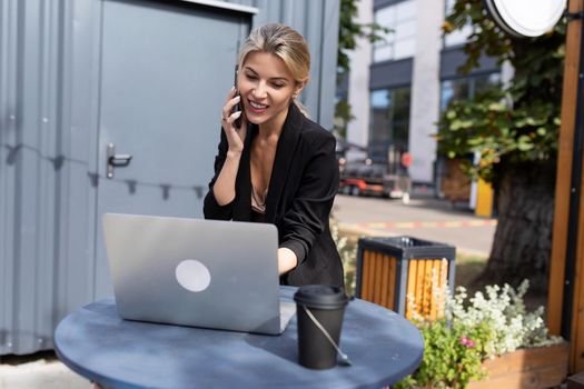 young successful woman working on a laptop in the street.