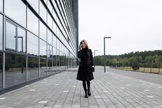 Middle-aged business woman rushing to work next to an office building with a smile on her face.