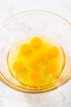 Mixing ingredients with a hand whisk in a glass mixing bowl to make egg bites.