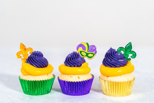 Mardi Gras vanilla cupcakes in foil cupcake cups and decorated with Italian buttercream frosting.